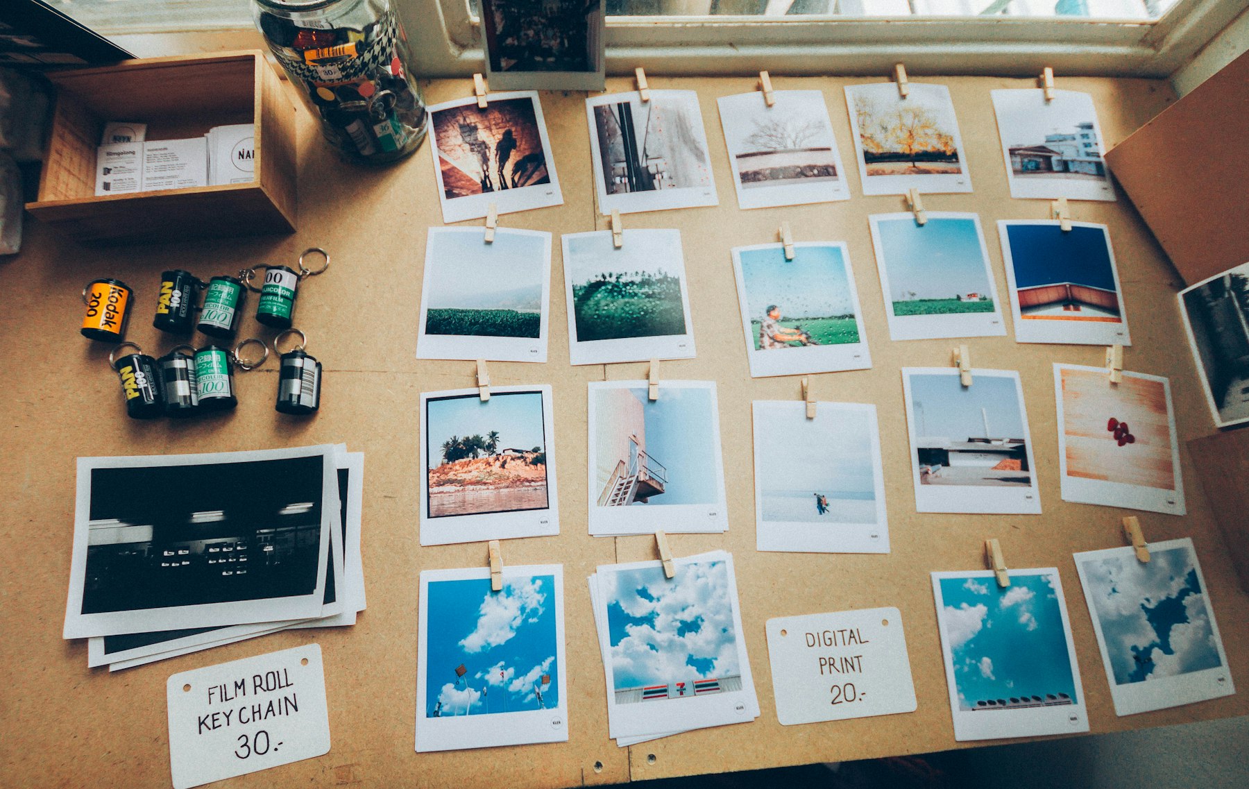 Rows of instant photos and prints laid out on a wooden table, sorted into a grid.